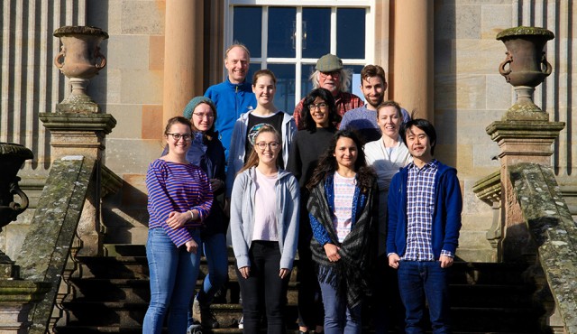 Lab group standing on stone steps in front of a stately home.